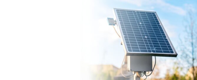 Ingeniero de energía solar con casco, usando un radio PTT y una tablet, mientras inspecciona la instalación de paneles solares industriales en una azotea.