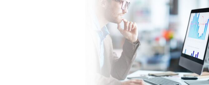 Hombre joven con gafas analizando gráficos de consumo energético en una pantalla de computadora, con la mano en la barbilla en señal de concentración.