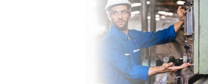 Ingeniero de mantenimiento con casco y gafas de seguridad, operando un panel de control en una planta energética industrial, con una tablet en la mano.